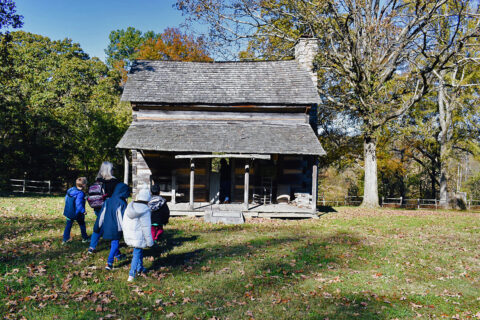 Children and chaperones walk towards one of the 16 buildings at Historic Collinsville during a group trip.
